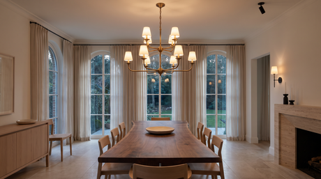 Two-tier brass chandelier with milk glass shades above a long walnut dining table
