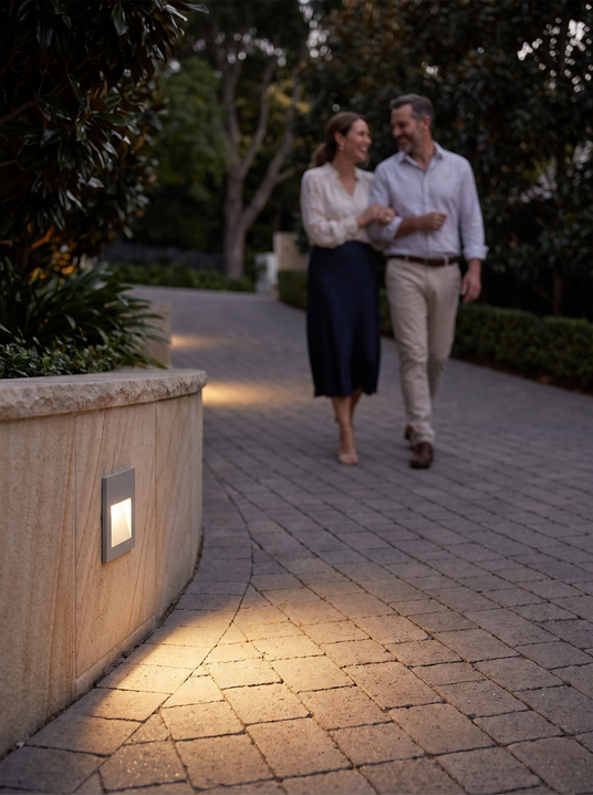 Albertine embedded step light along a driveway wall