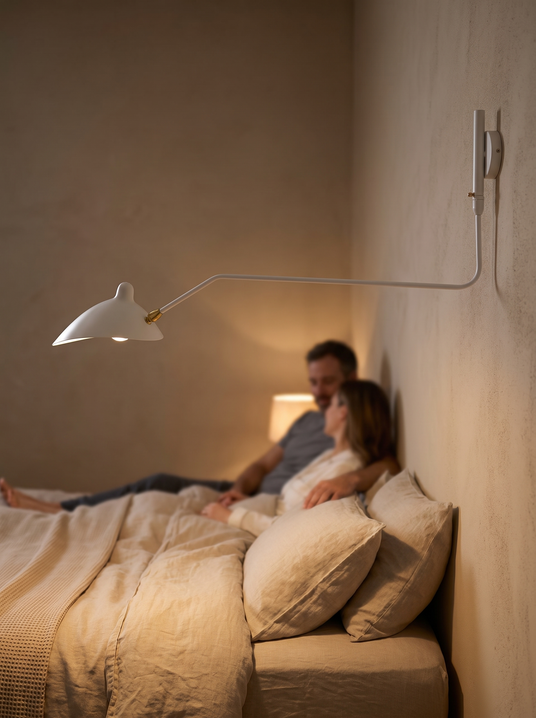 Serge Mouille swing arm wall sconce reaching over a bed